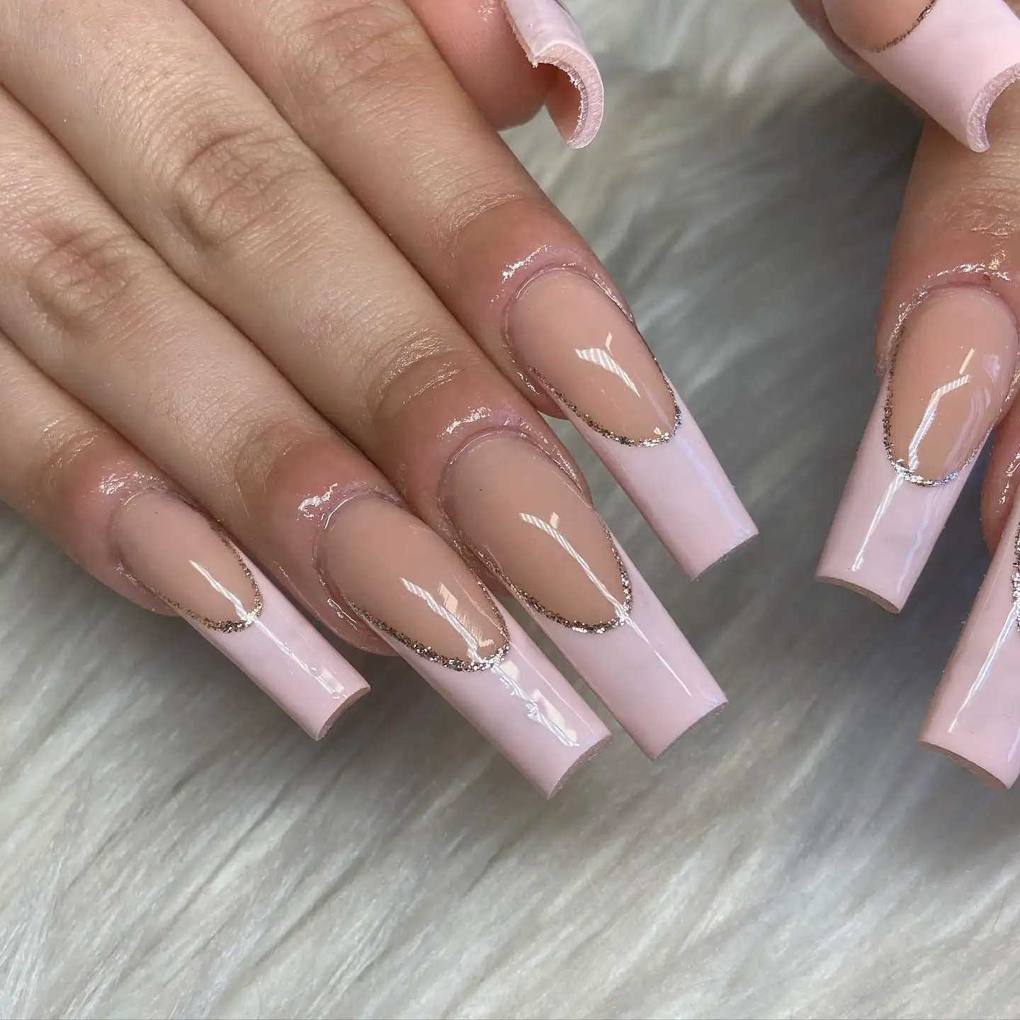 Short round nails with alternating horizontal gold and white stripes on a sheer nude base.