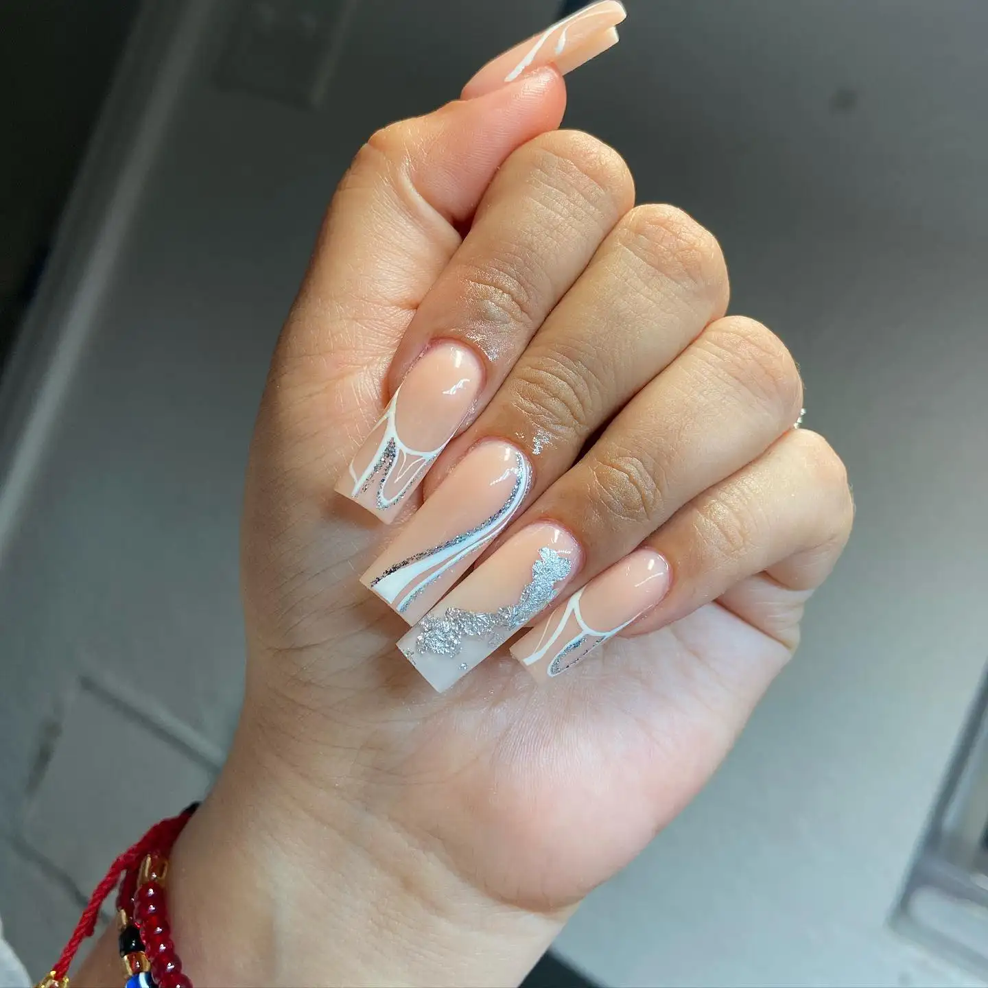 Short natural nails with gold glitter polish and fine white diagonal stripes over a nude base.