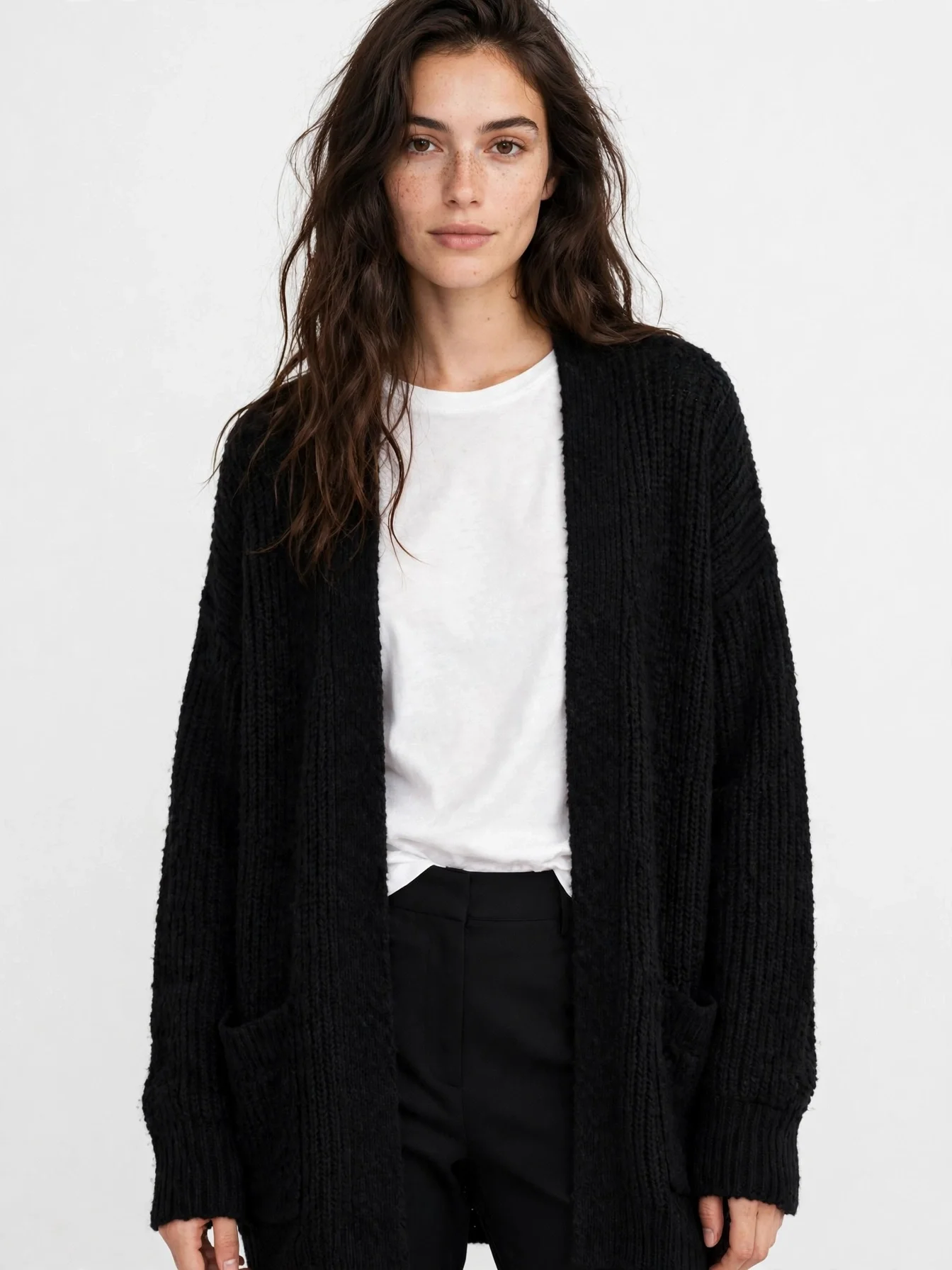 Long black open oversized cardigan worn over a white top and black pants