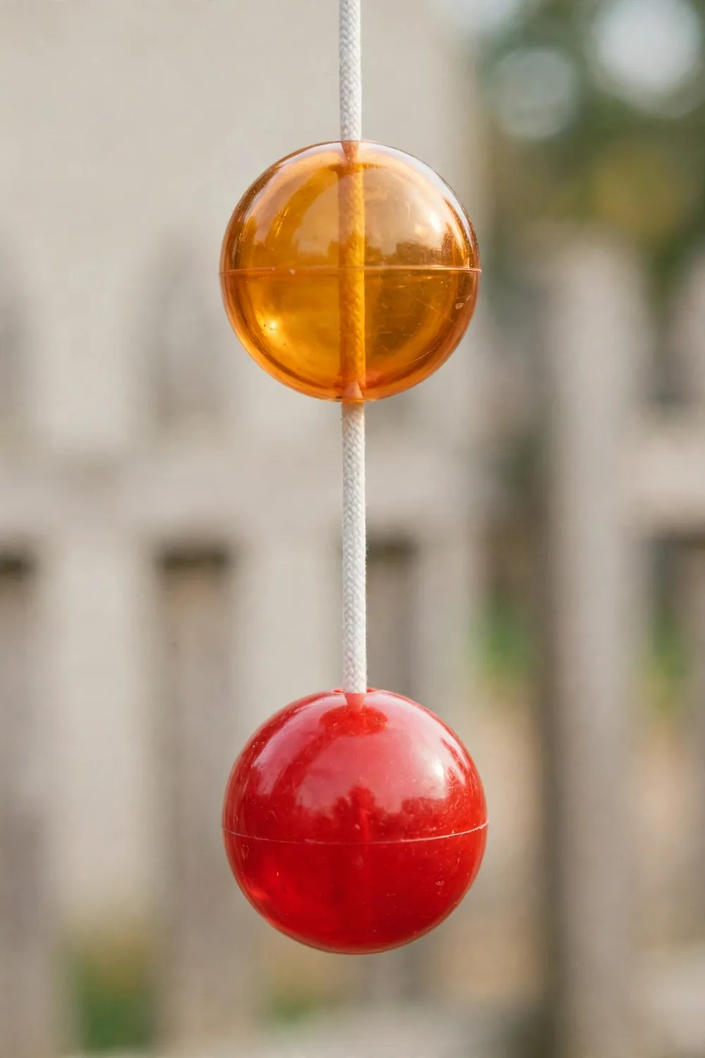 Two hard acrylic balls on strings, a vintage click-clack toy
