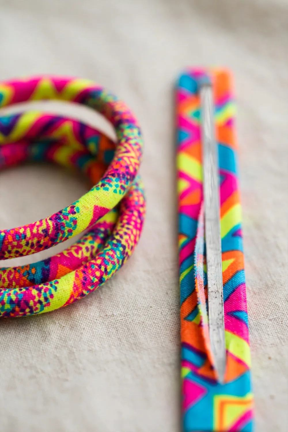 A colourful eighties-style slap bracelet curled beside its straight metal strip