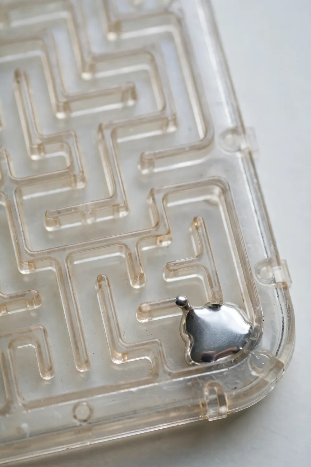 A handheld plastic tilt maze puzzle with a silvery liquid metal blob inside