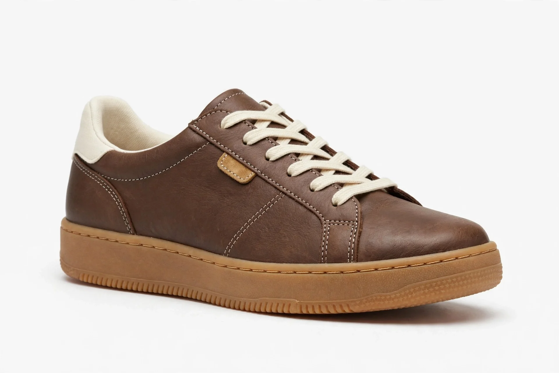 Single brown leather low sneaker with cream laces, a tan gum sole, a cream heel tab, a small tan accent, and white stitching