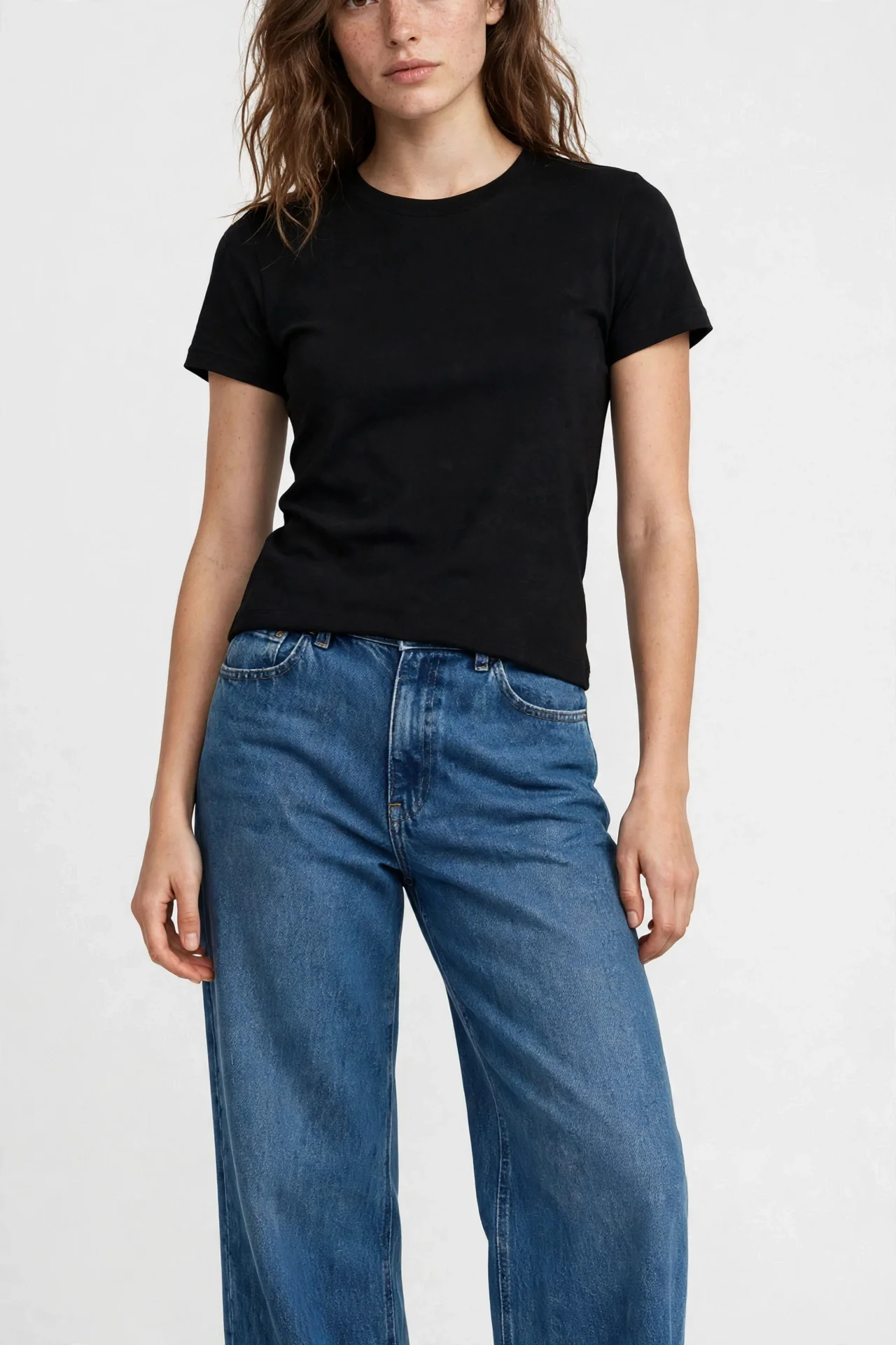 Model in medium-blue wide-leg jeans, black top, black shoes