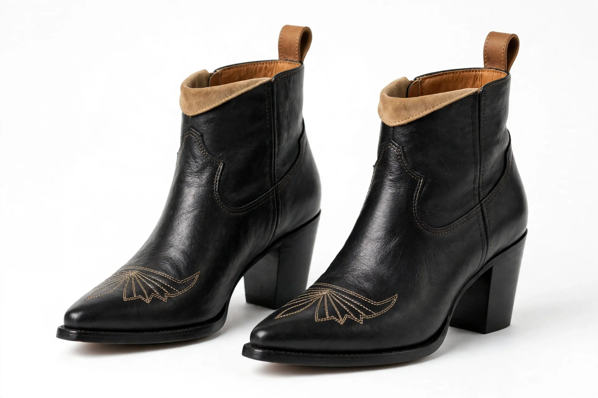 Pair of black leather western ankle boots with pointed toes, block heels, decorative toe stitching, tan lining at the top, and rear pull tabs