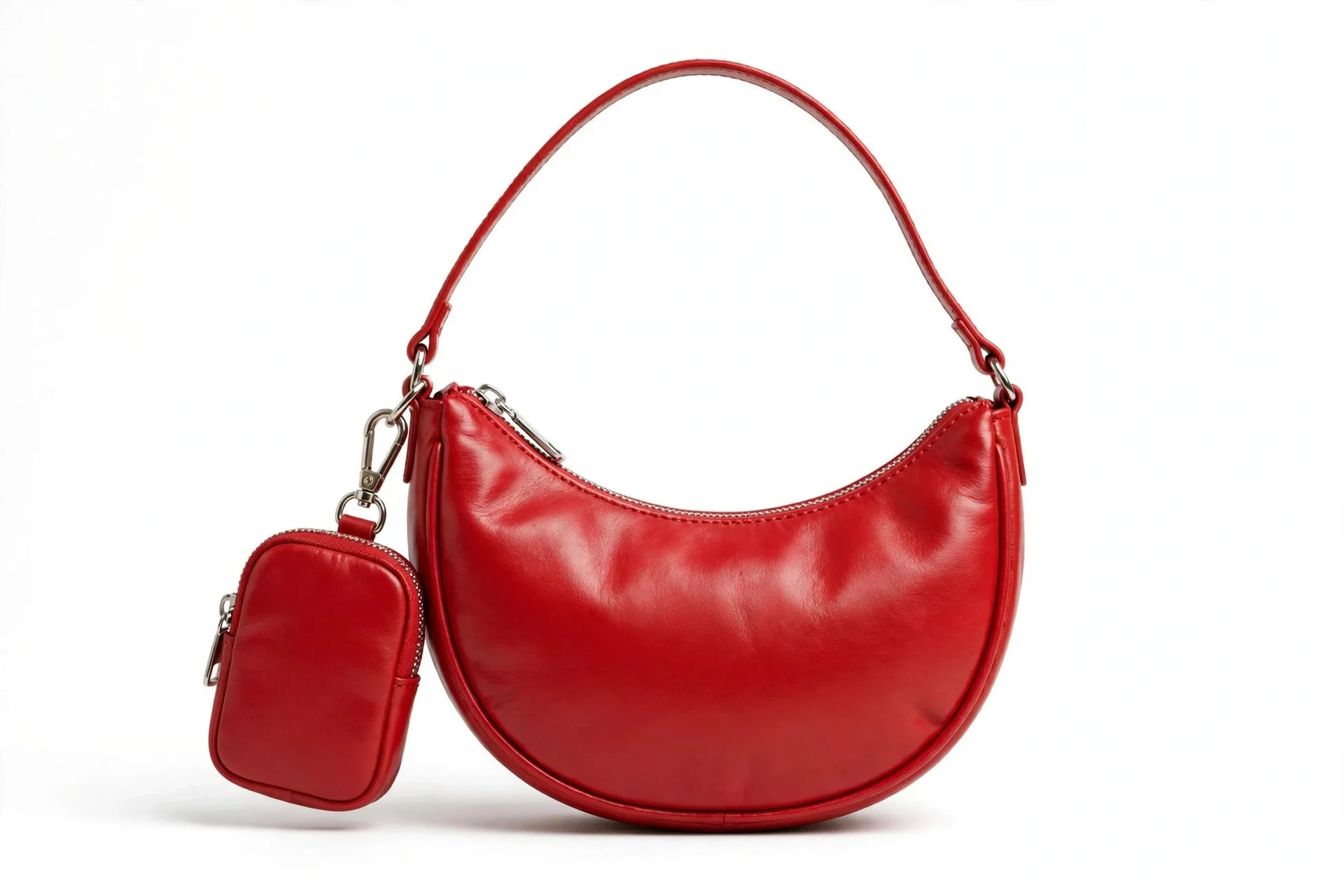 Bright red crescent-shaped small shoulder bag with a thin strap and a small zip pouch attached