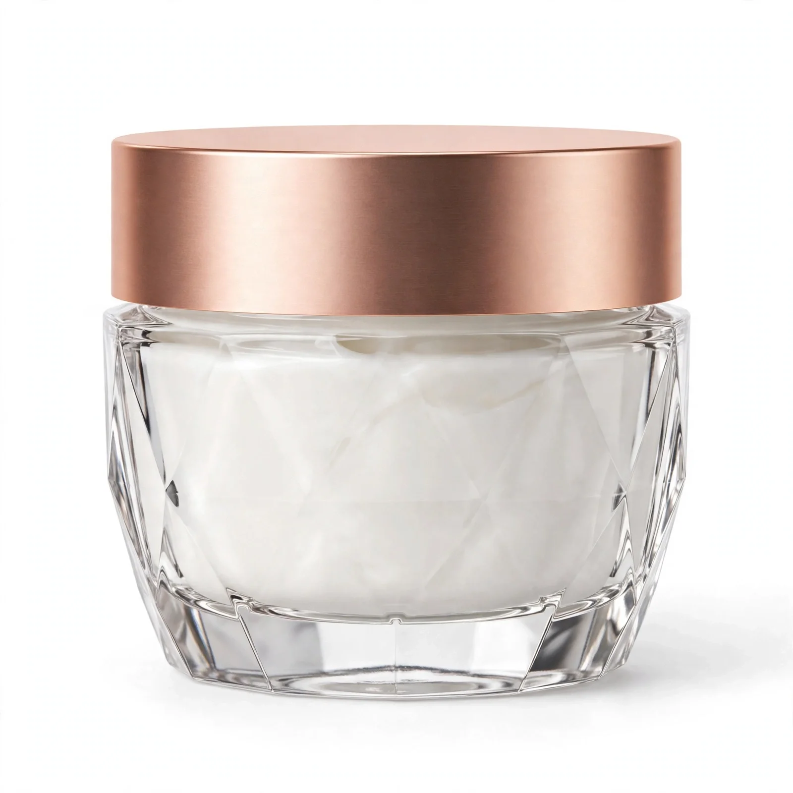 Clear faceted glass jar of white face cream with a wide rose-gold lid