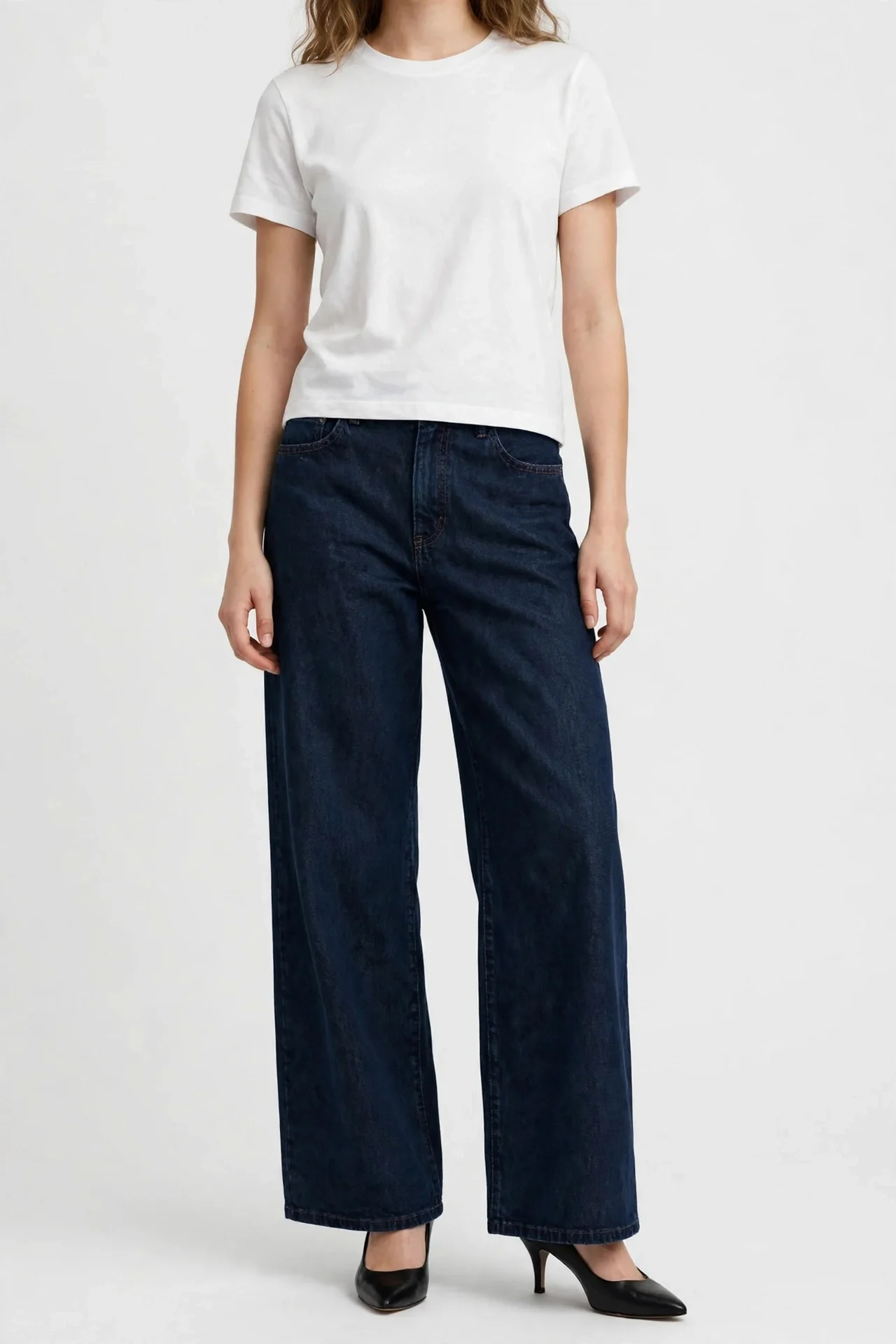 Model in dark navy wide-leg jeans, white top, dark heeled shoes