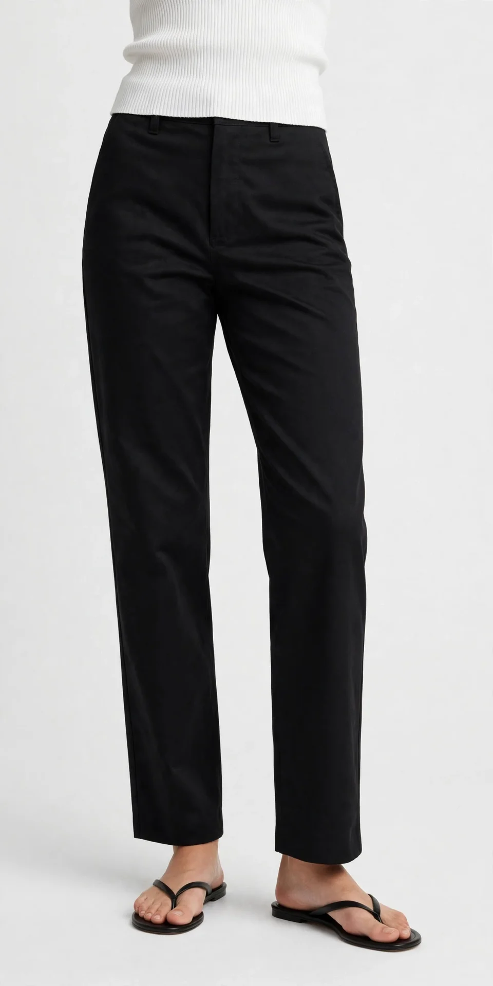 Black straight-leg pants worn with a white ribbed crop top and black flat thong sandals