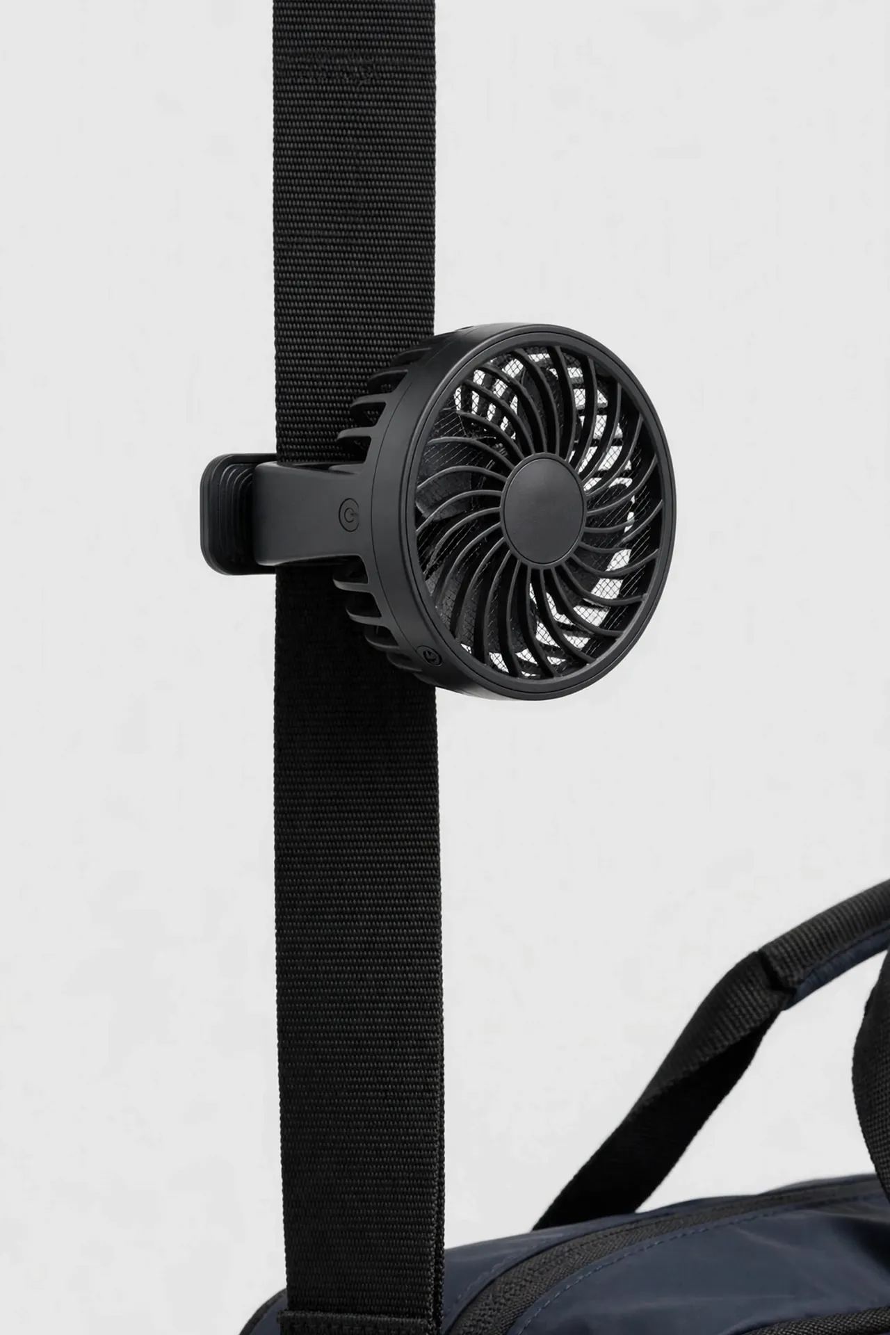 Small clip-on fan attached to a bag strap
