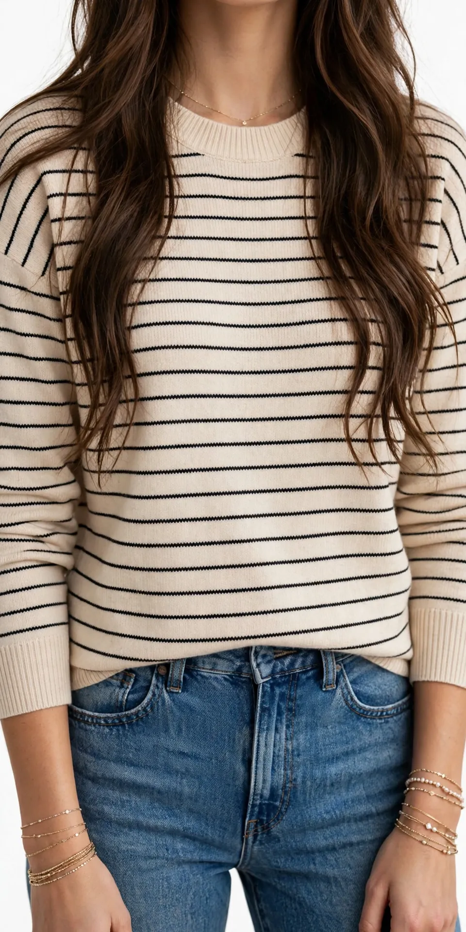 Cream crewneck sweater with thin black horizontal stripes, worn with blue jeans
